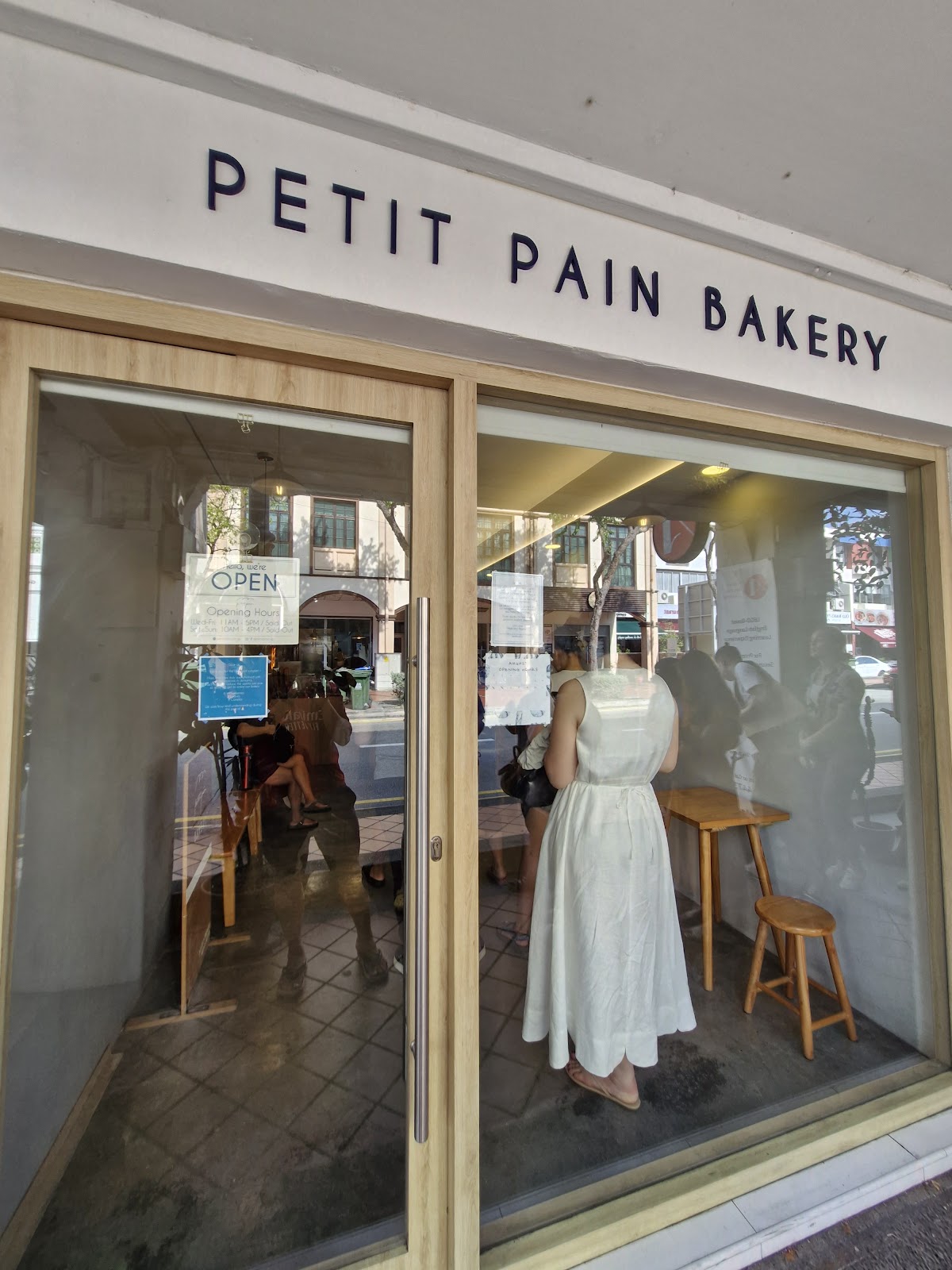 The Petit Pain Bakery shopfront sign with customers inside