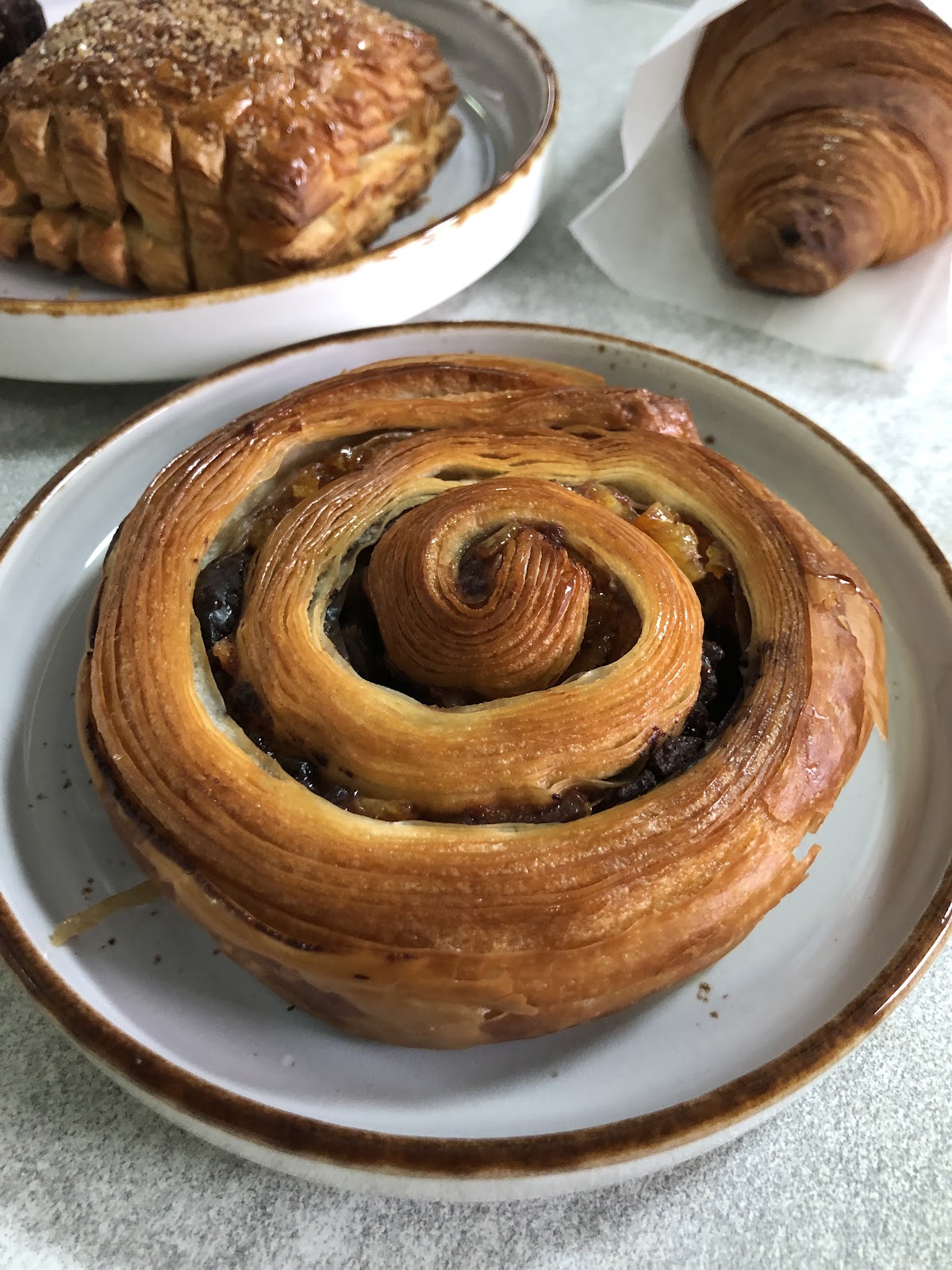 A raisin escargot with a pain au chocolat behind it